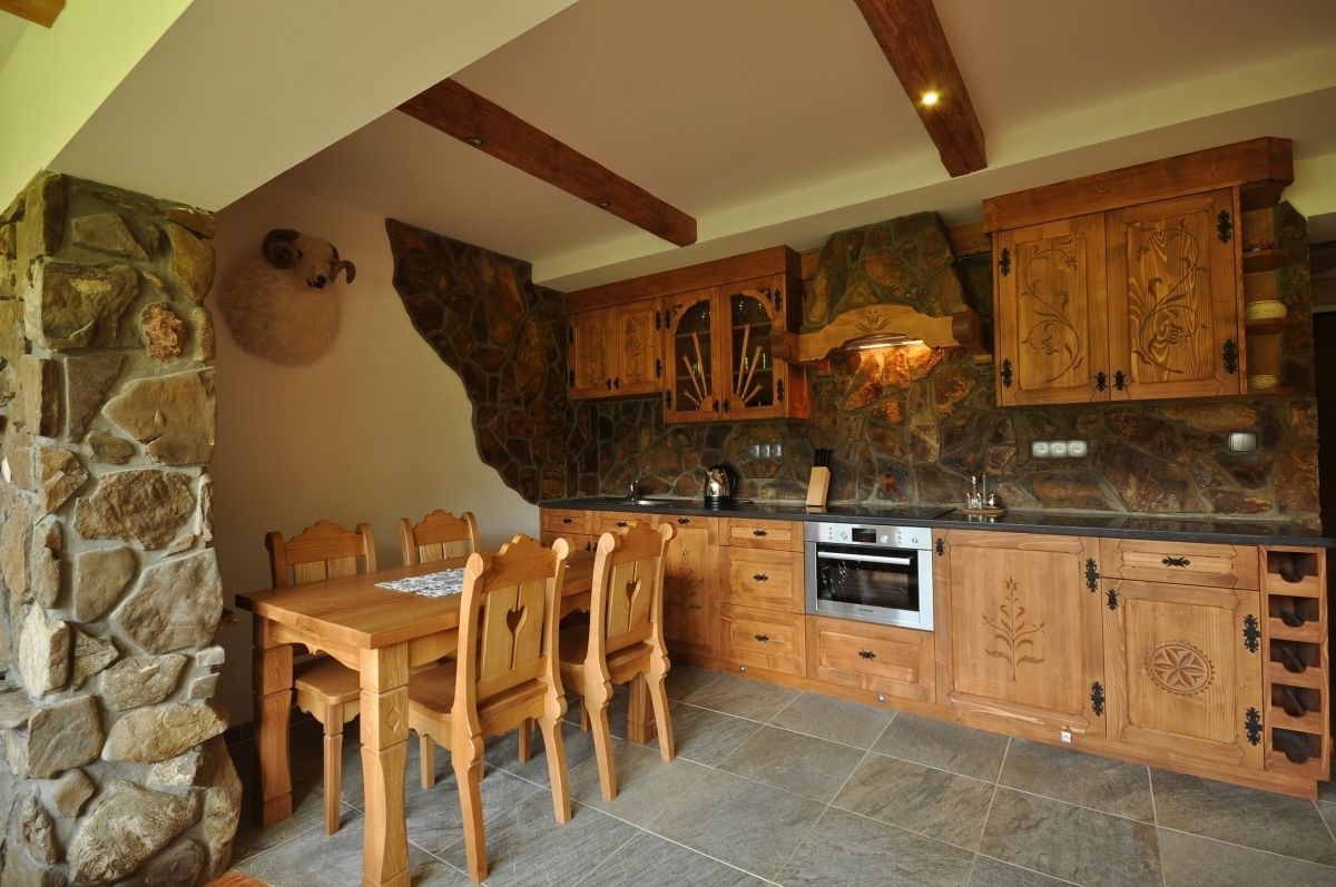 Una cocina rústica con paredes de piedra, armarios de madera y una mesa de comedor con sillas.