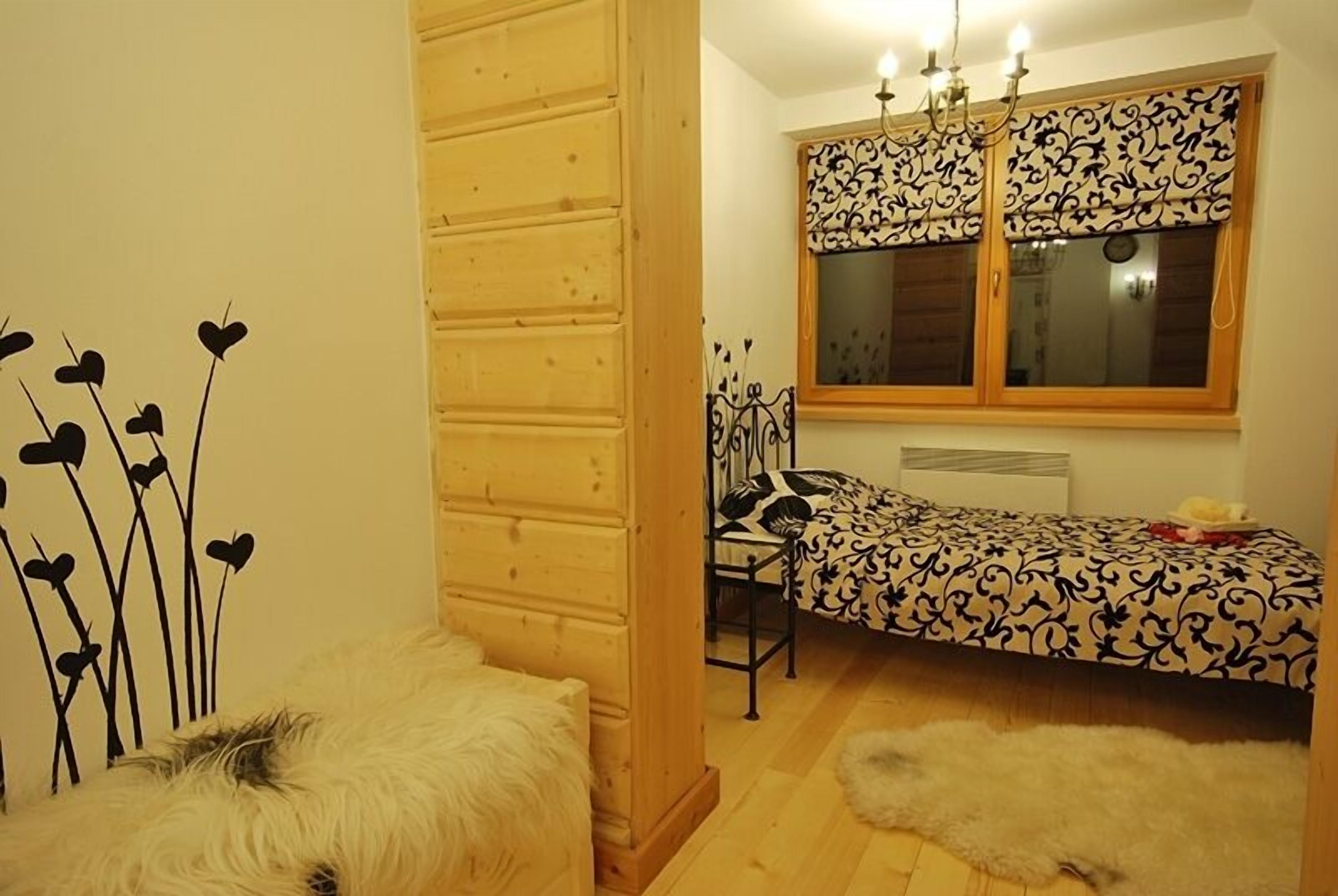Une pièce confortable avec un lit, une chaise, une fenêtre ornée de rideaux à motifs et un tapis moelleux.