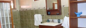 Un baño con lavamanos, espejo y perchero para toallas.