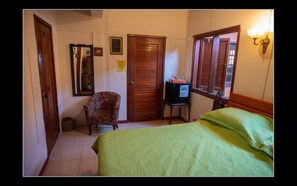 Un dormitorio con cama, silla, televisor y puerta.