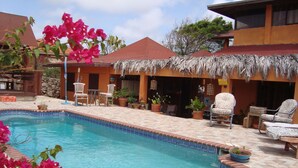 Una piscina con borde de azulejos, rodeada de plantas en macetas y mobiliario de exterior.