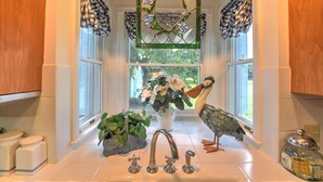 Una cocina con un ventanal grande, un espejo decorativo y una escultura de pájaro.