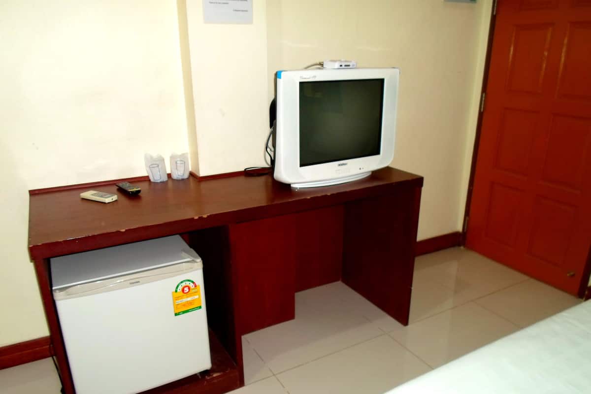 A small kitchenette with a refrigerator, a microwave, and a coffee maker. There is a television on a wooden desk.