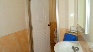 Ein Badezimmer mit weißer Tür, Waschbecken, Spiegel und Handtuchhalter.