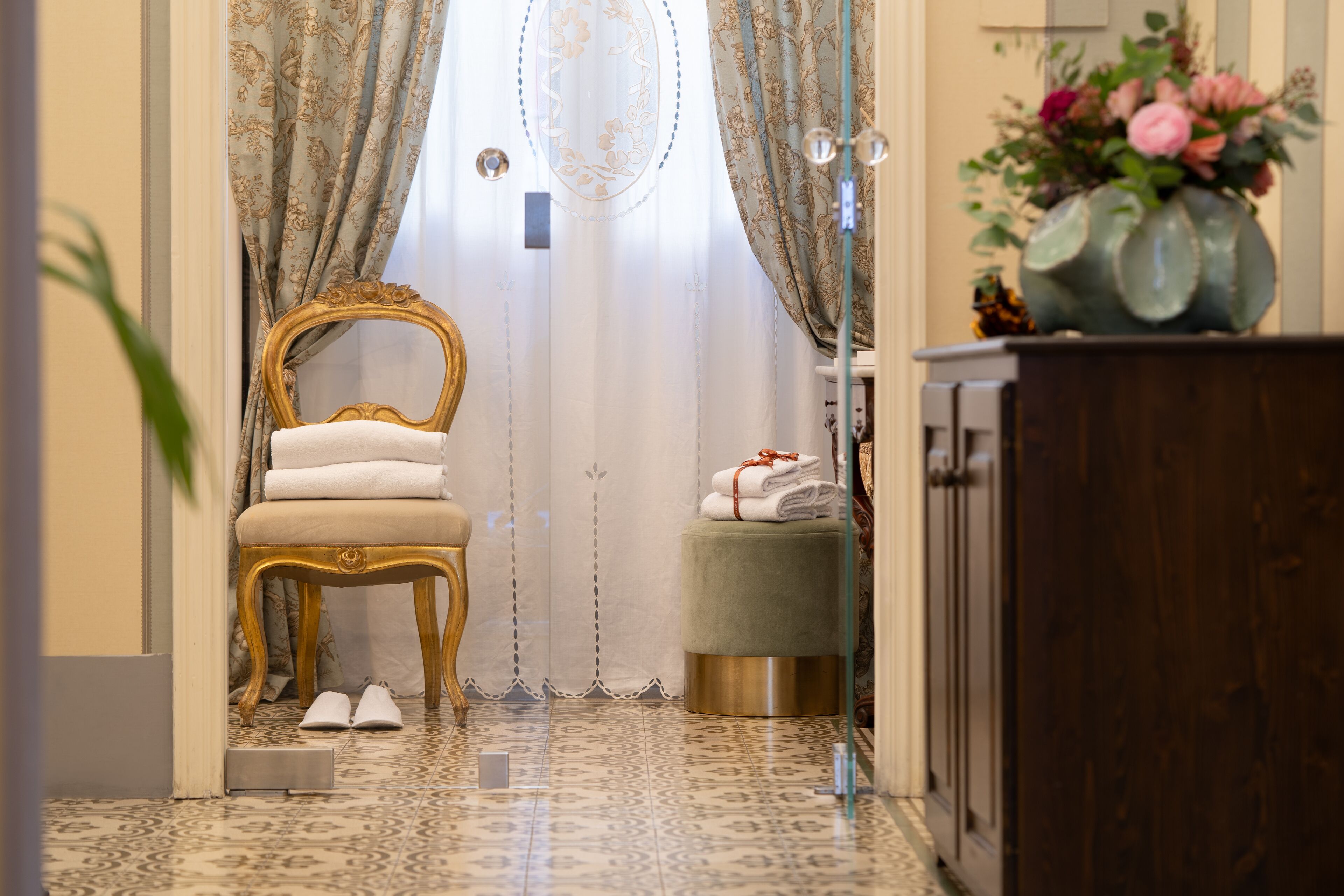 A room with a chair, ottoman, and a cabinet.
