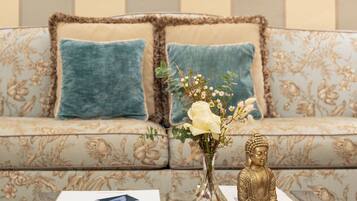 A living room with a sofa, a glass coffee table, a Buddha statue, and a framed mirror on the wall.