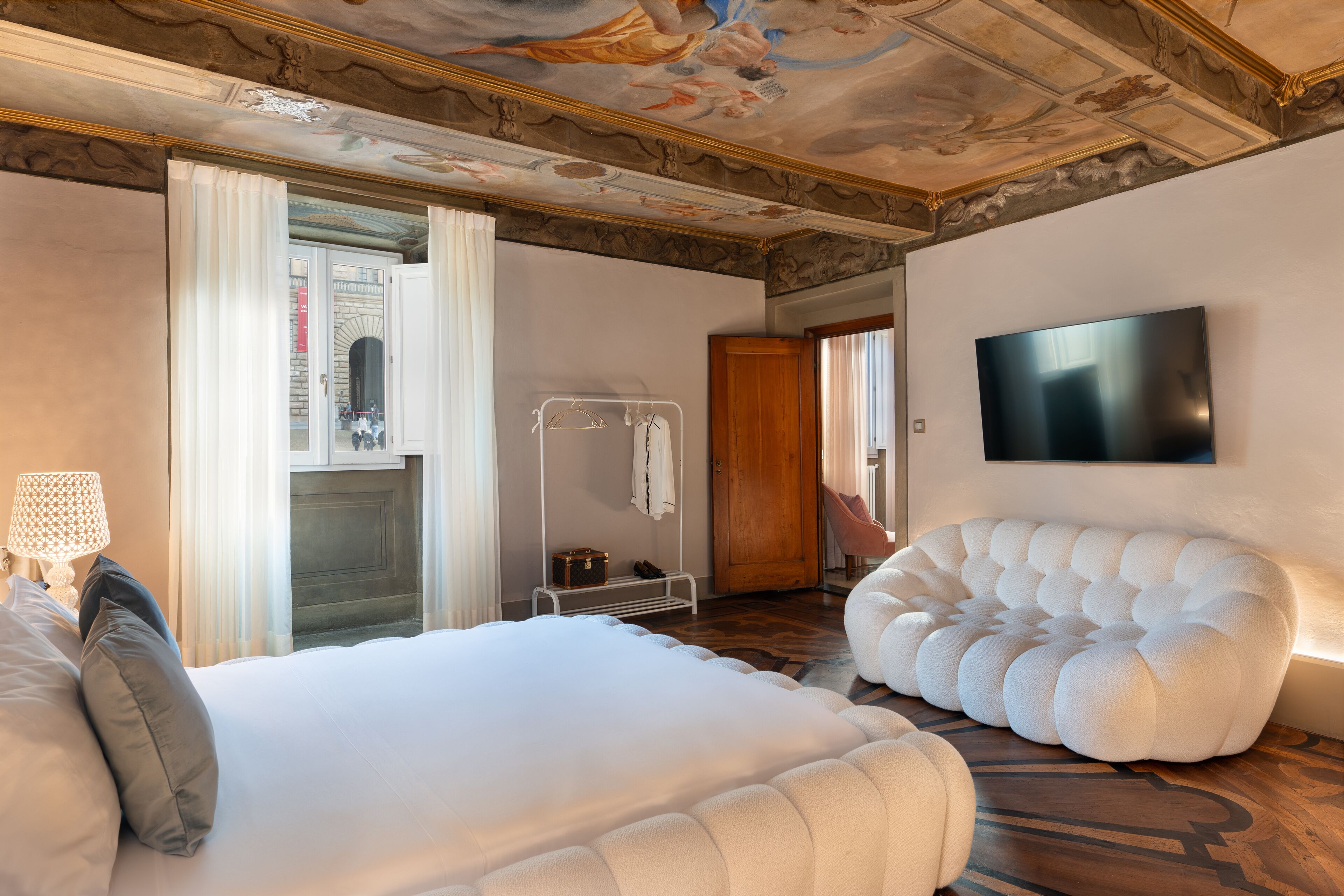 Ein modernes Hotelzimmer mit einem großen Bett, einer Sitzecke, einem Flachbildfernseher und einer dekorativen Decke.