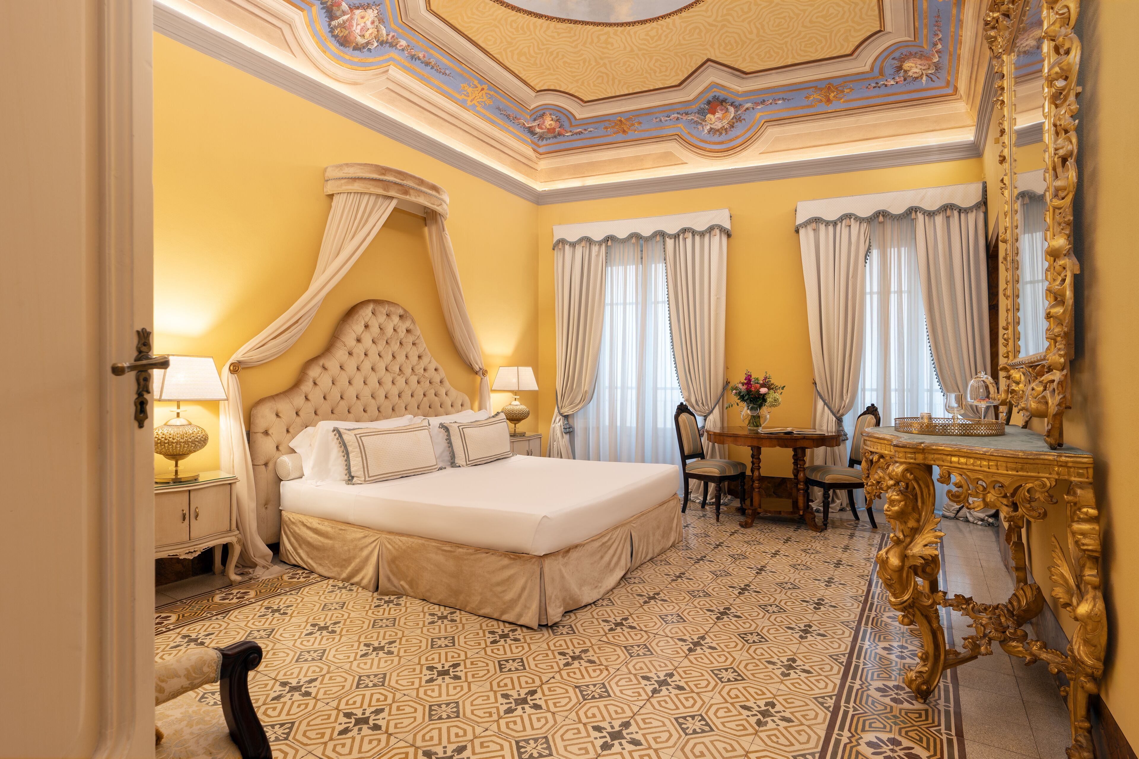 Ein luxuriöses Schlafzimmer mit einem großen Bett, einer aufwendigen Decke und einem klassischen Kronleuchter.