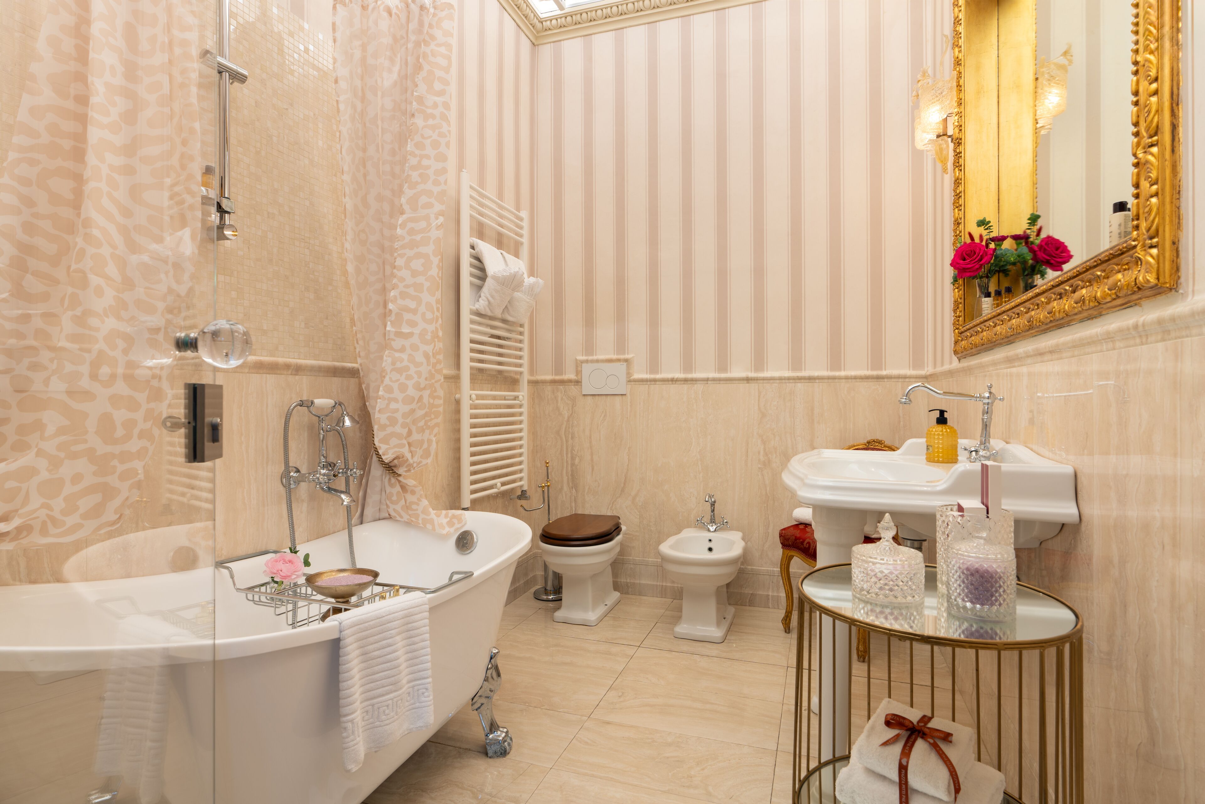 A luxurious bathroom with a freestanding bathtub, a pedestal sink, and a bidet.