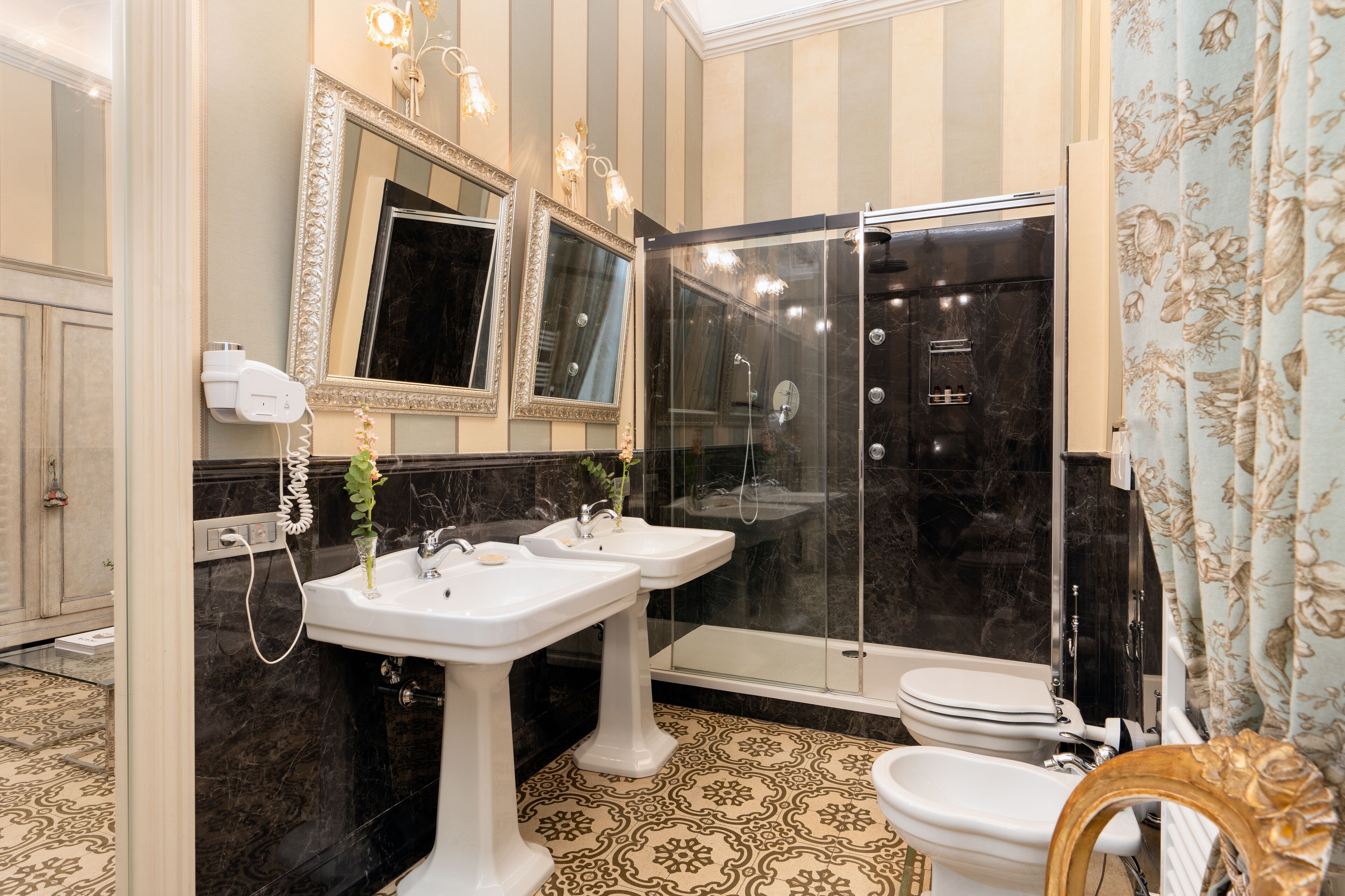 A bathroom with two sinks, a toilet, a shower, and a vanity mirror.