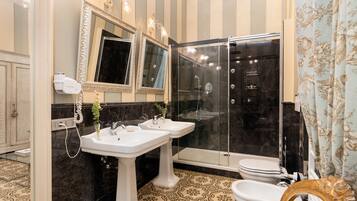 A bathroom with two sinks, a toilet, a shower, and a vanity mirror.