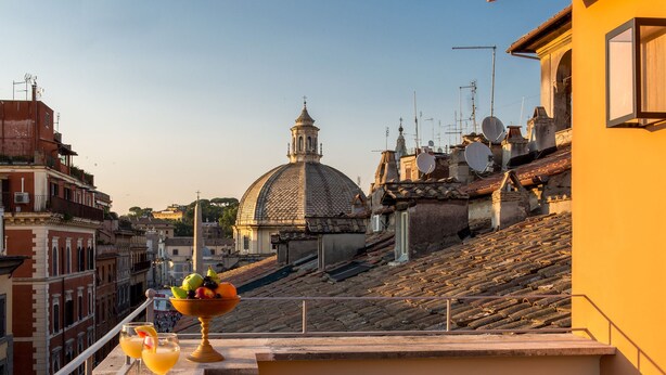 Eine Terrasse mit Tisch für zwei Personen mit Blick auf eine historische Stadtlandschaft, geprägt von einer markanten Kuppel und traditioneller Architektur.