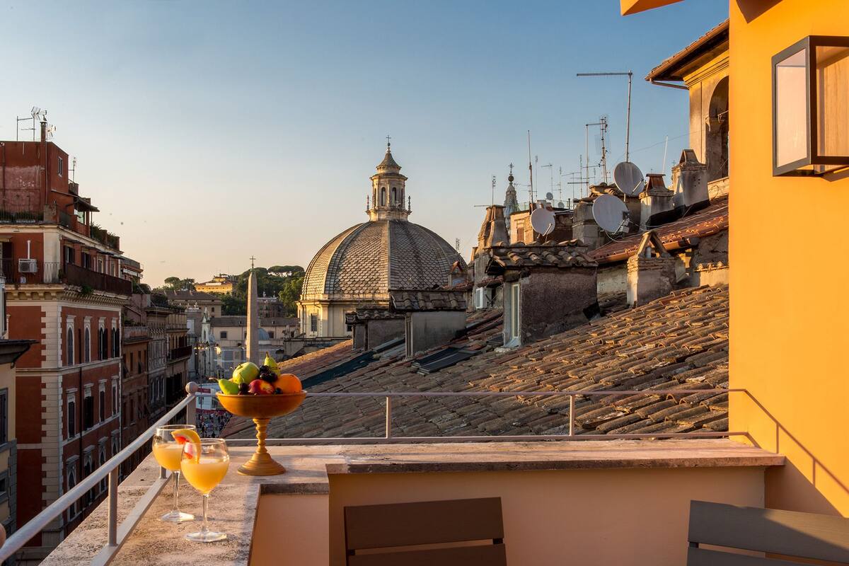 A terrace with a table set for two, overlooking a historic cityscape with a prominent dome and traditional buildings.