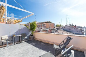 A rooftop terrace with a table and chairs, a potted plant, and a view of the cityscape. - Rarity Suites (Rome)