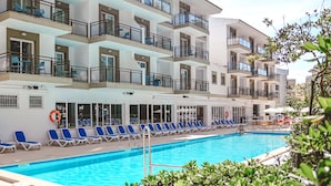 A multi-story hotel with balconies, a swimming pool, and sun loungers. - Guya Wave Hotel (Capdepera)