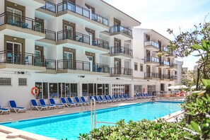 Una piscina techada, una piscina al aire libre, sombrillas