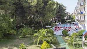 A resort with a swimming pool, outdoor seating, and lush greenery. - Guya Wave Hotel (Capdepera)