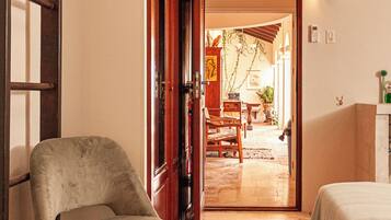 A room with a bed, a chair, and a wooden door leading to a dining area.