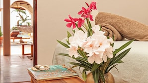 A wooden bench with a vase of flowers and a book on it. - Goood Resort (Kralendijk)