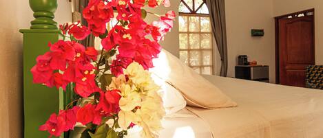 Ein Schlafzimmer mit einem Bett, einem grünen Blumenvasen und einem Fenster mit Vorhängen.