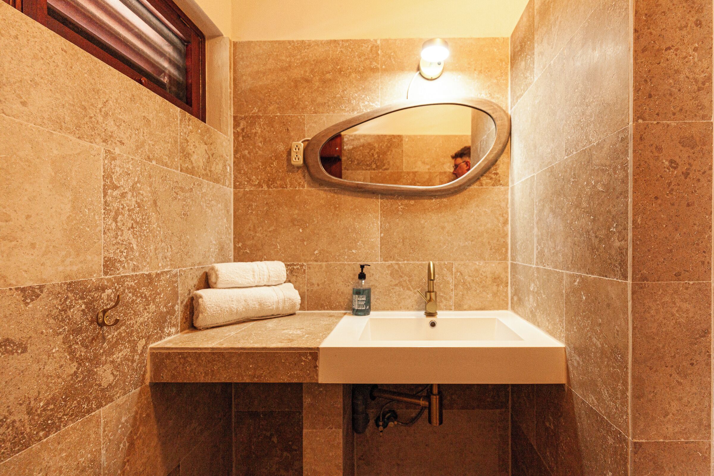 A bathroom with a white sink, a mirror, and a towel rack.