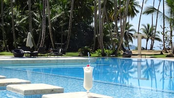 Una piscina al aire libre, sombrillas, sillones reclinables de piscina