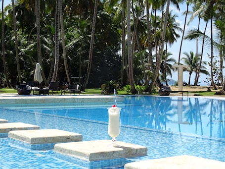 Una piscina al aire libre, sombrillas, sillones reclinables de piscina