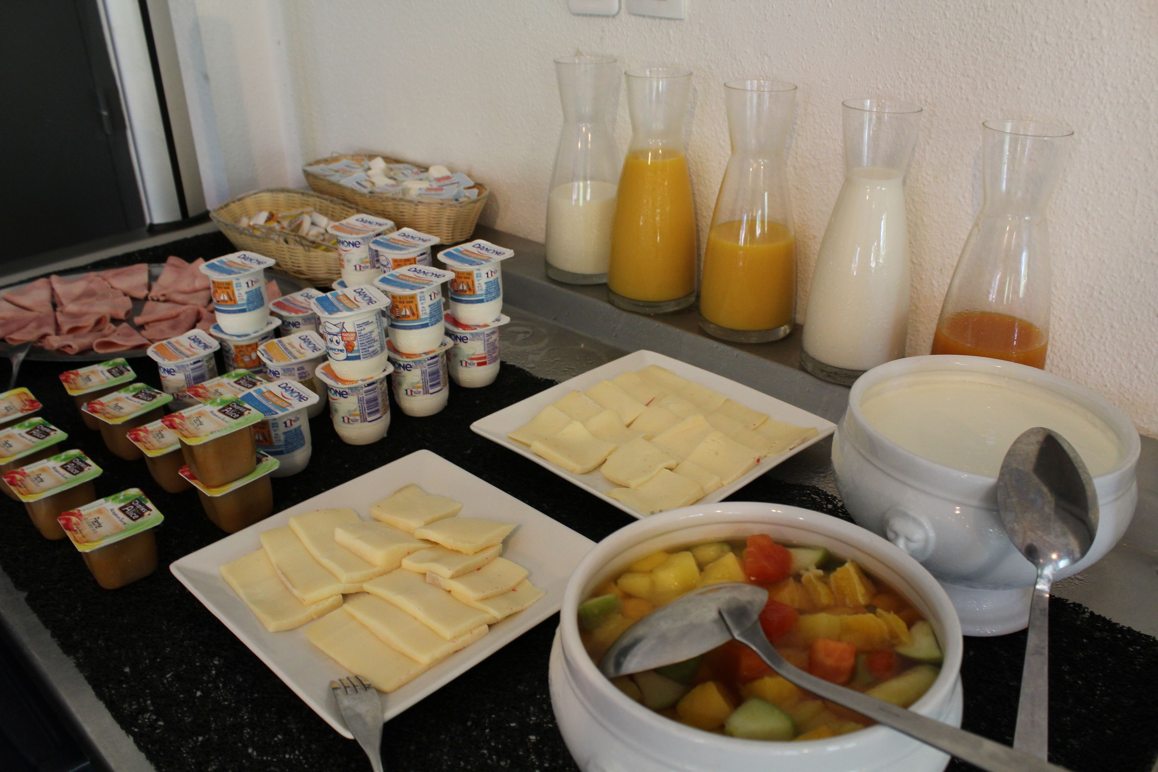 A breakfast buffet with various dairy products, cheese, and fruit salad.