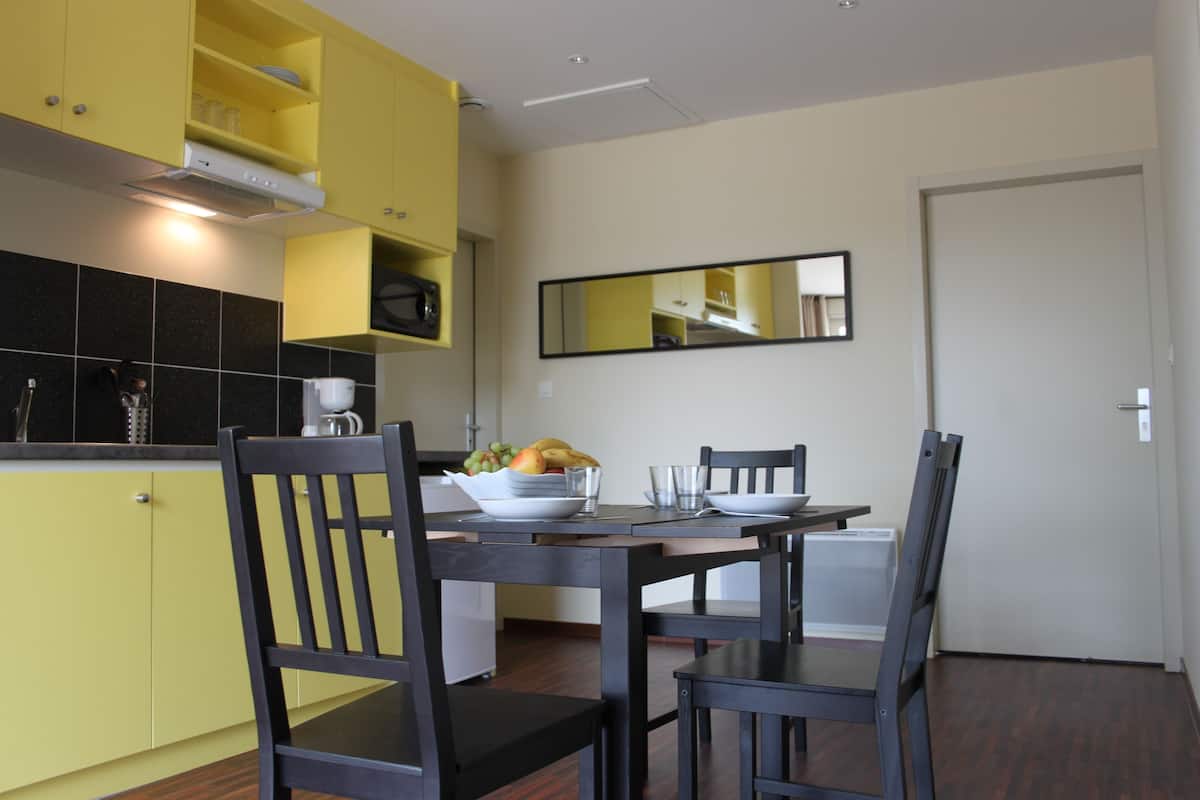 A modern kitchen with yellow cabinets, a dining table with chairs, and a large mirror on the wall.