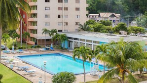 Un hotel con piscina, palmeras y vistas a una colina.