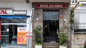 La entrada del Hotel São Jorge, con un cartel llamativo, el número '52' y dos plantas en macetas a la entrada.