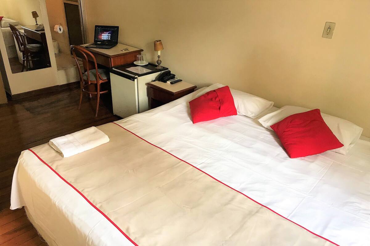 Une chambre d’hôtel comprenant un lit, un bureau avec un ordinateur, une chaise et un téléphone.