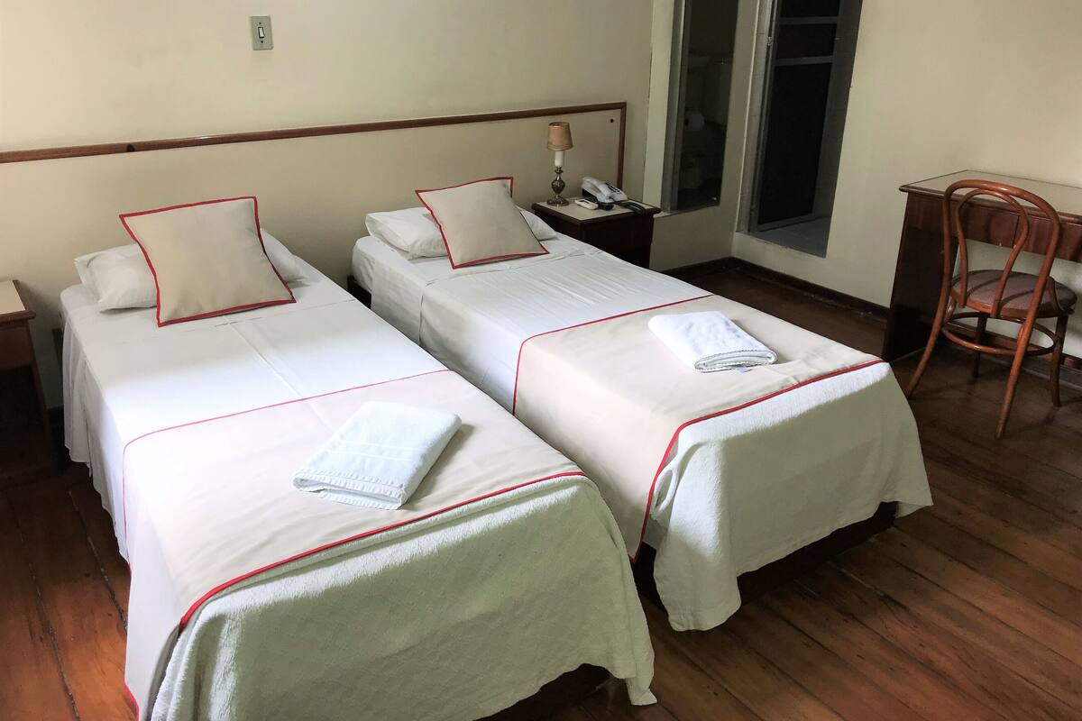 Une chambre d’hôtel avec deux lits simples, chacun étant équipé d’un oreiller et d’une serviette pliée.