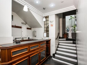Una cocina moderna con una isla de madera, una escalera que sube a una plataforma, y vistas al exterior.