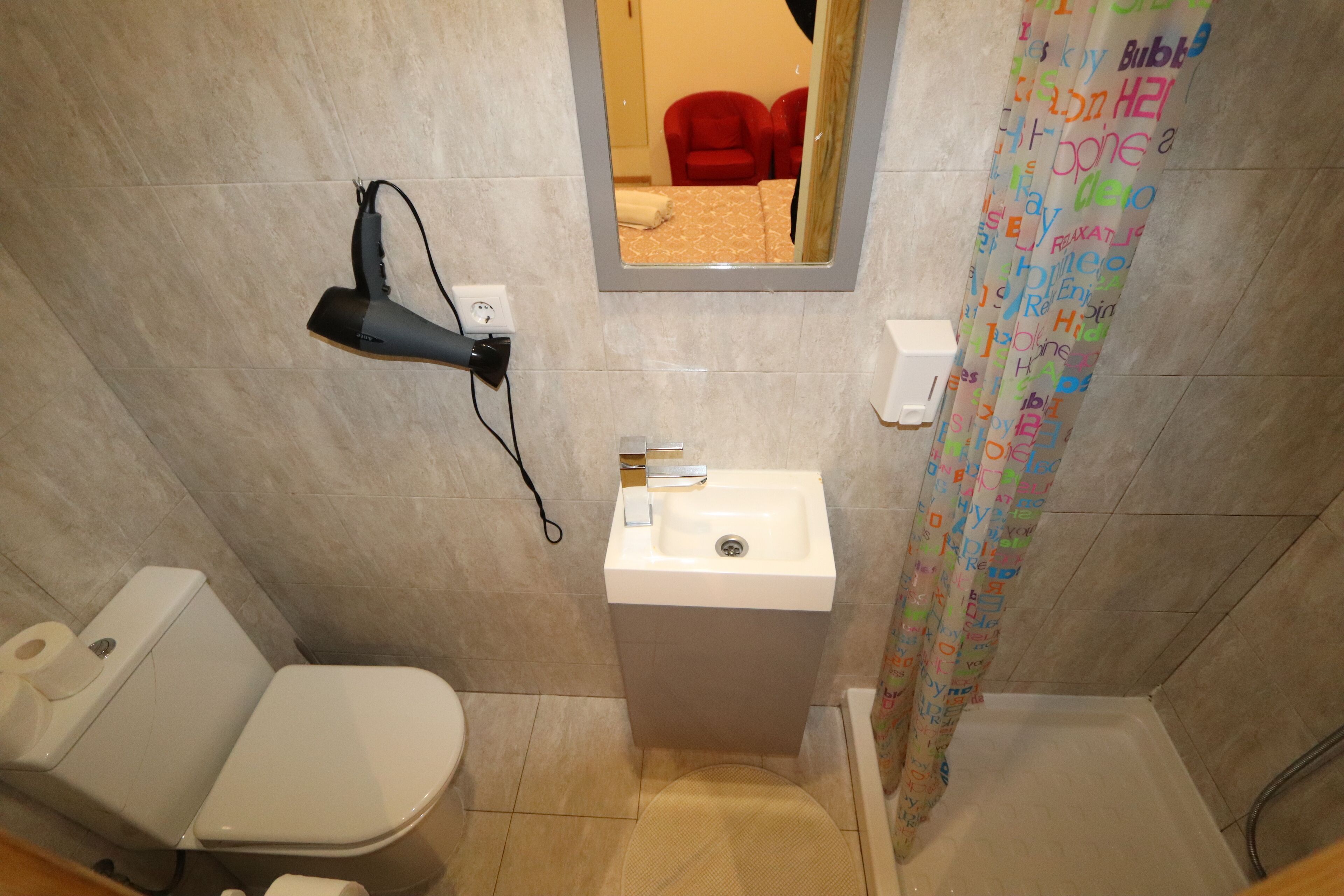 Une salle de bain équipée de toilettes, d’un lavabo et d’un rideau de douche.