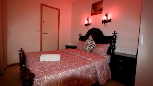A bedroom with a large bed, a nightstand, a dresser, and a wall-mounted lamp. - Welcome Guest House - Hostel (Lisbon)