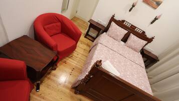 A bedroom with a wooden bed, a red armchair, and a wooden nightstand.
