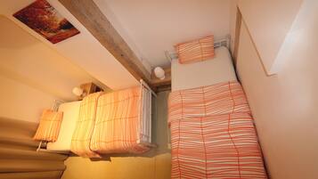 Un dormitorio con dos camas, cada una con ropa de cama a rayas, un radiador y un cuadro en la pared.