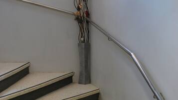 Un escalier avec une rampe métallique et un vase rempli de fleurs.