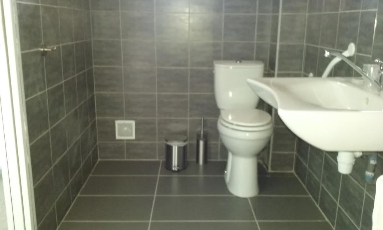 Une salle de bain équipée de toilettes, d’un lavabo et d’une poubelle.