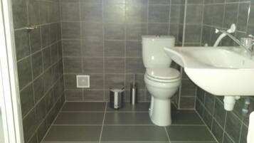 Une salle de bain équipée de toilettes, d’un lavabo et d’une poubelle.
