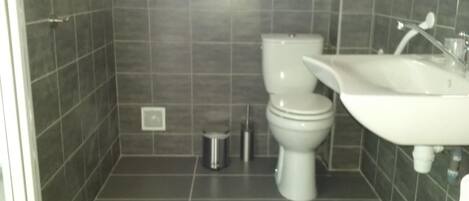 Une salle de bain équipée de toilettes, d’un lavabo et d’une poubelle.