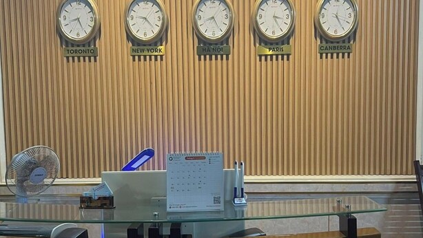 Una recepción en el Hotel Kim Long, con relojes mostrando la hora de Toronto, Nueva York, Hanói, París y Canberra.
