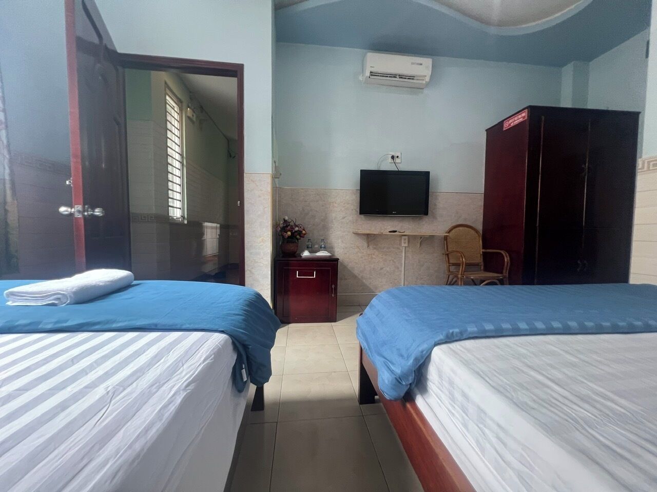 Une chambre d’hôtel avec deux lits, une télévision, une armoire et un appareil de climatisation.