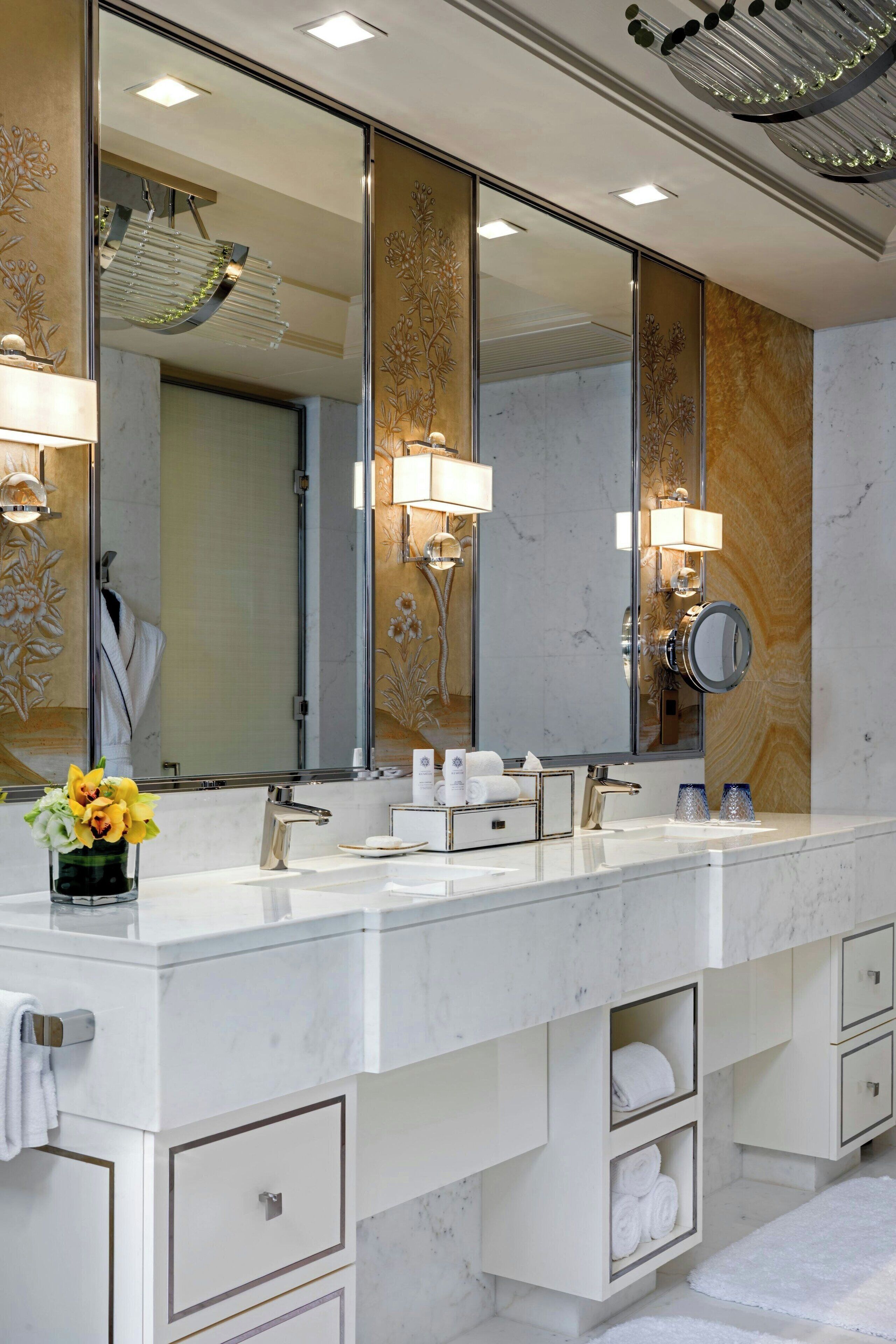 Un baño moderno con un espejo grande, dos lavabos y espacio para toallas integrado.