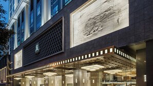 Una entrada de hotel moderna con un mural grande, una fachada geométrica y un amplio vestíbulo.