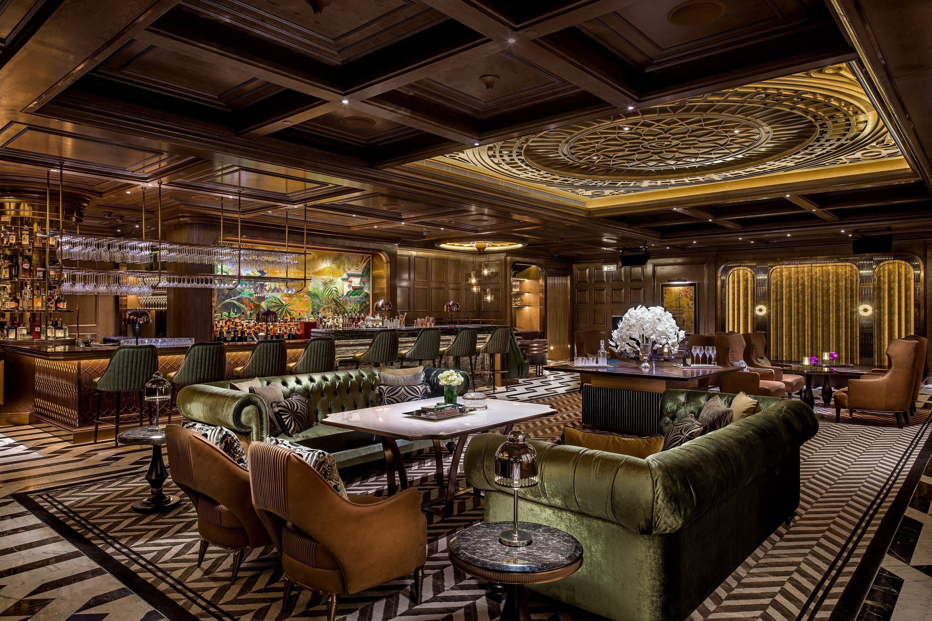 A luxurious lounge area with plush seating, a bar, and a decorative ceiling.