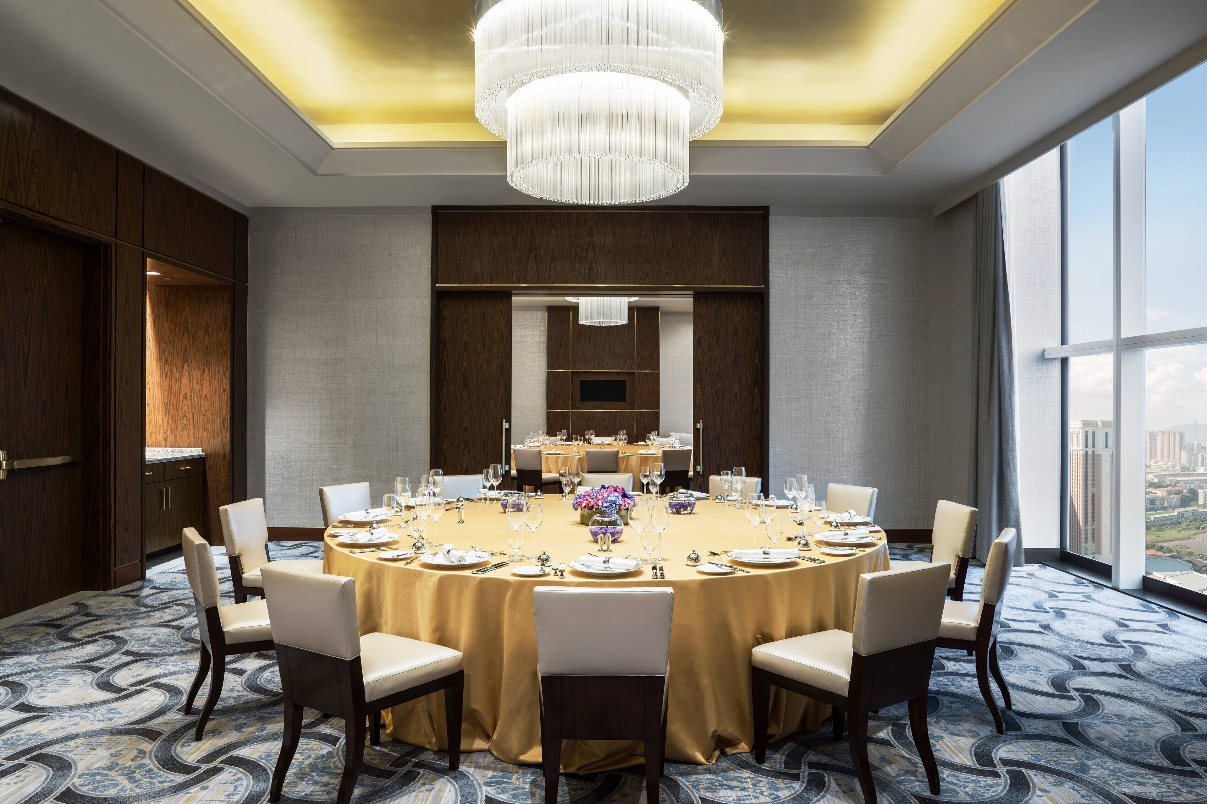 Une salle de conférence dotée d’une grande table ronde, de chaises et d’un lustre.