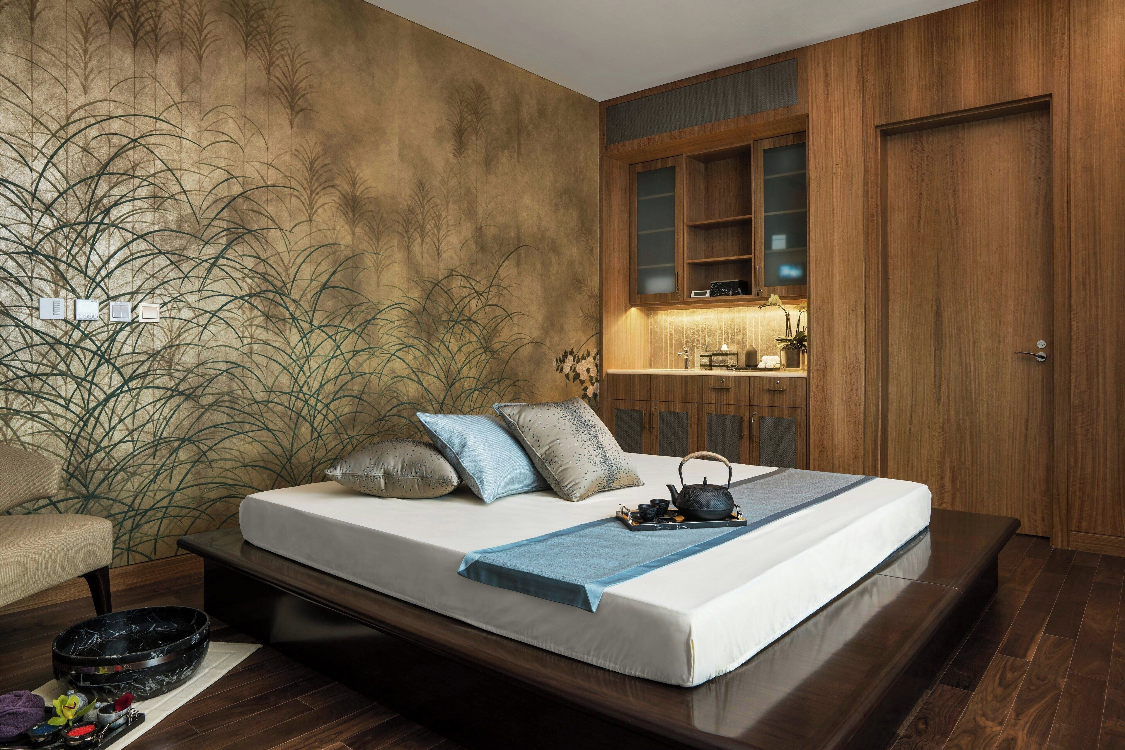 A modern bedroom with a large bed, wooden cabinets, and a small kitchen area.