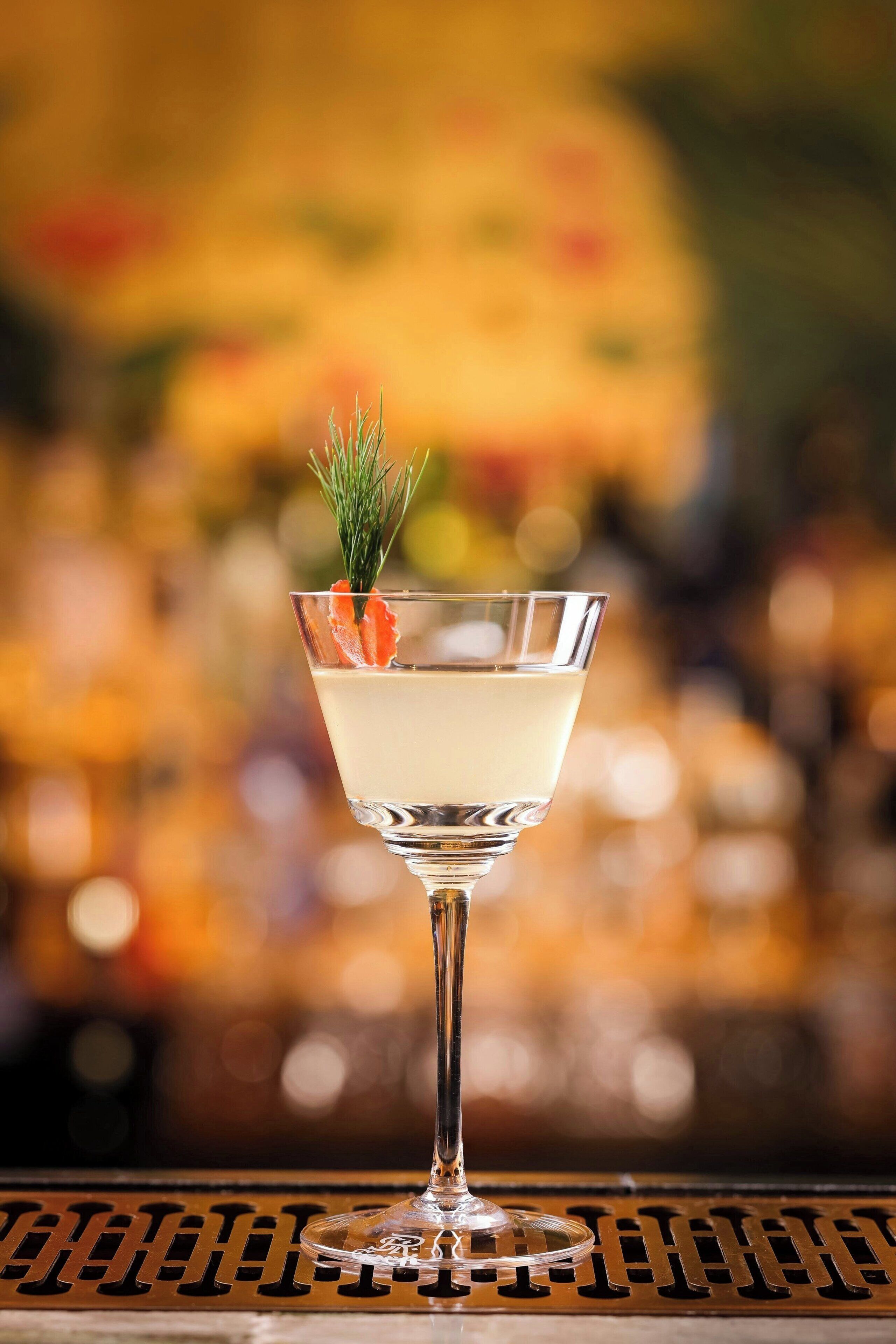 A martini glass with a garnish on a bar counter.